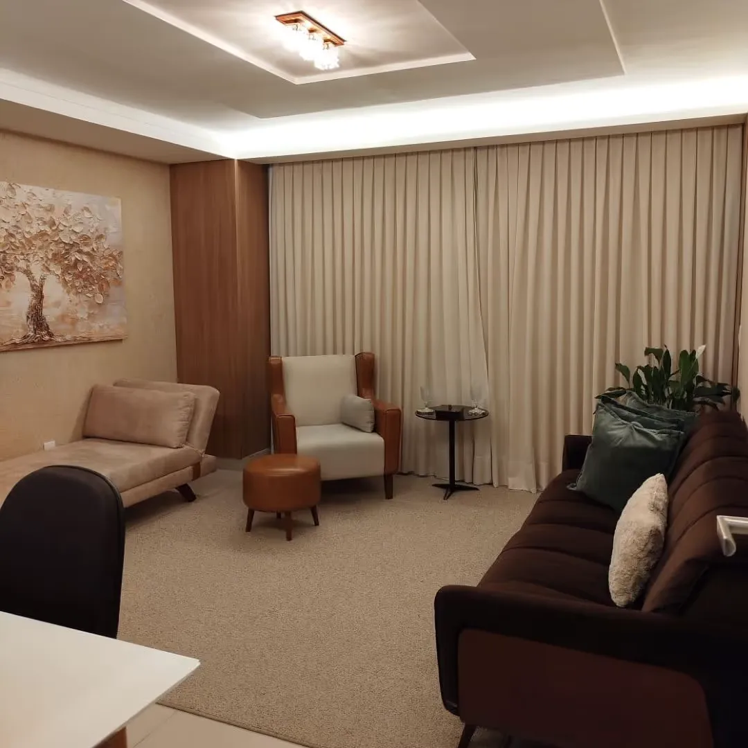 Sala de atendimento do Instituto Pensare com sofá, poltronas, cortinas claras e iluminação indireta